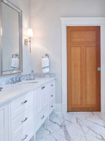 home care supply white bathroom with marble counters and a wooden door