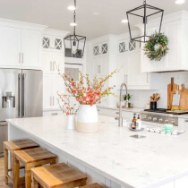 home care supply white kitchen with a central island and wooden stools creating a modern and inviting space